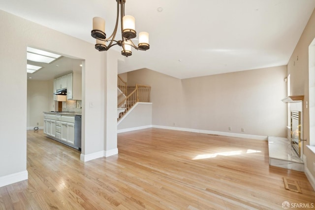 unfurnished living room with a chandelier and light hardwood / wood-style flooring