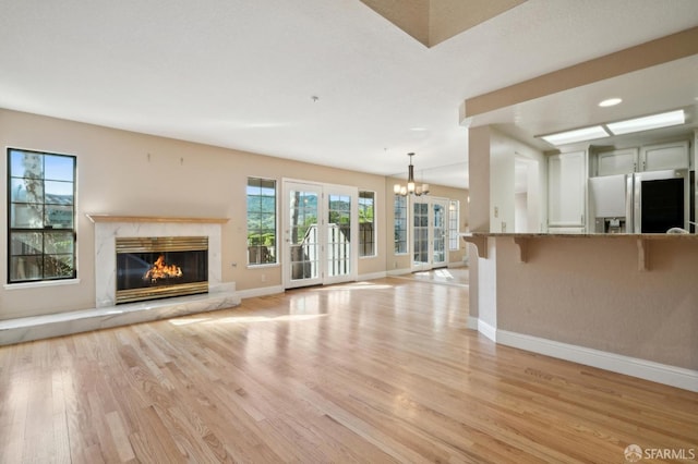 unfurnished living room featuring a chandelier, a fireplace, and light hardwood / wood-style floors