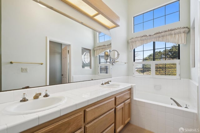 bathroom featuring a relaxing tiled tub and vanity