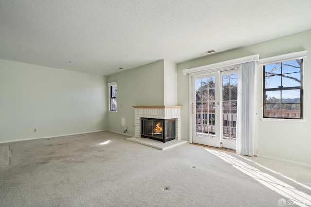 unfurnished living room featuring plenty of natural light, a fireplace, and carpet floors