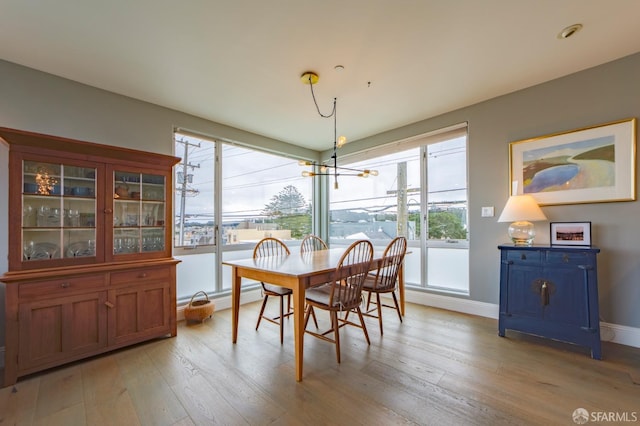 dining space with light wood-type flooring and baseboards