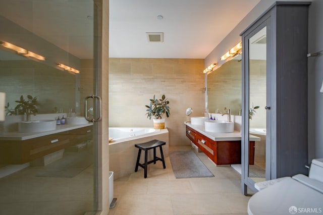 full bath with toilet, a garden tub, tile patterned flooring, vanity, and tile walls