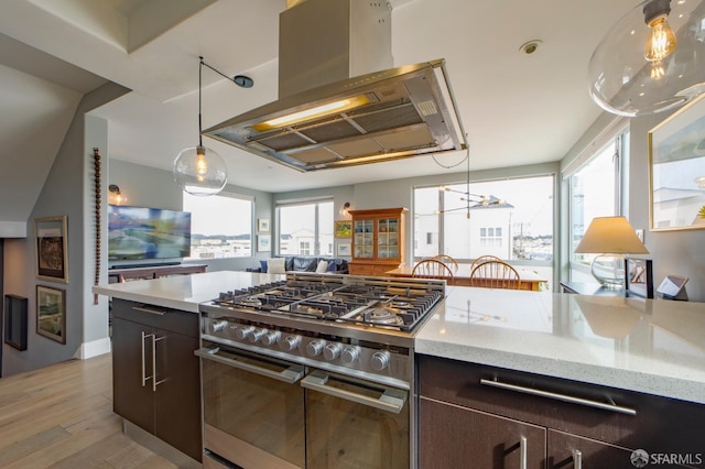 kitchen with island exhaust hood, light wood-style floors, dark brown cabinets, light stone countertops, and double oven range