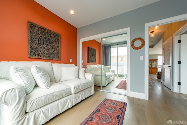 living area with baseboards, light wood finished floors, and recessed lighting