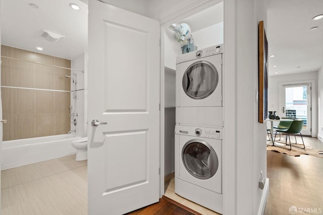 washroom with stacked washing maching and dryer and hardwood / wood-style flooring