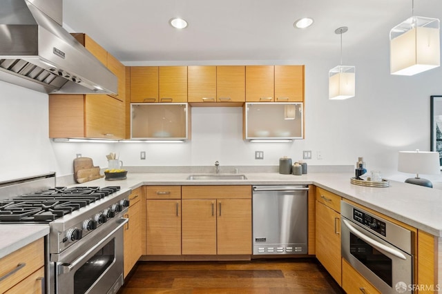 kitchen featuring stainless steel appliances, light brown cabinets, wall chimney range hood, and pendant lighting