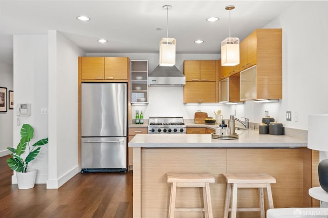 kitchen with stainless steel appliances, decorative light fixtures, wall chimney exhaust hood, kitchen peninsula, and a breakfast bar area