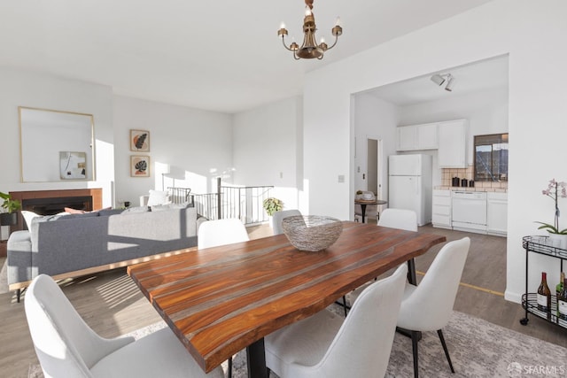 dining room featuring hardwood / wood-style flooring, a tiled fireplace, and a chandelier