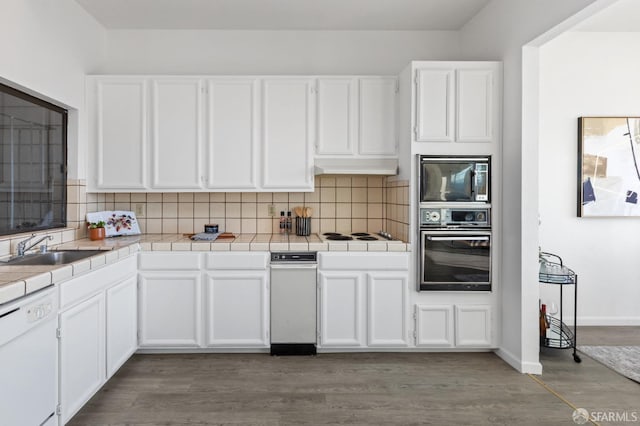 kitchen with white cabinetry, sink, decorative backsplash, tile counters, and white appliances