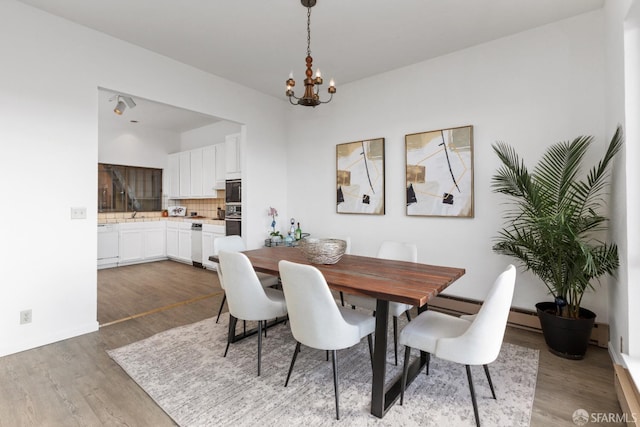 dining space featuring hardwood / wood-style flooring, a baseboard radiator, and a notable chandelier