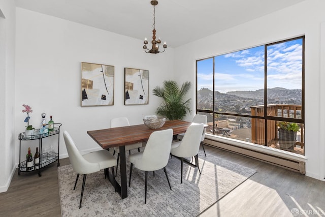 dining room featuring a mountain view, hardwood / wood-style flooring, a notable chandelier, and baseboard heating