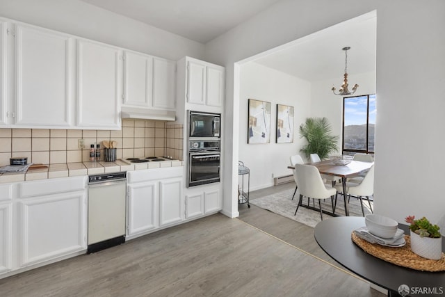 kitchen with white cabinetry, tile countertops, black appliances, pendant lighting, and backsplash