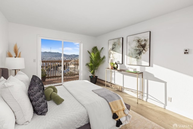 bedroom featuring hardwood / wood-style flooring, a mountain view, and access to outside