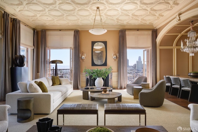 living room with a notable chandelier, a wealth of natural light, and crown molding