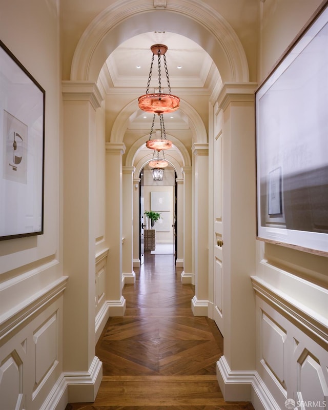 hall featuring a notable chandelier, crown molding, and dark parquet flooring