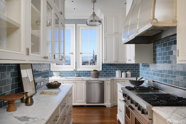 kitchen with light stone counters, white cabinets, decorative light fixtures, backsplash, and exhaust hood