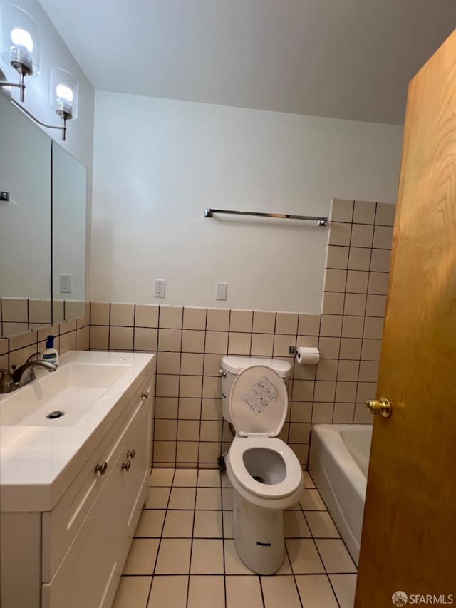 bathroom with vanity, a bathtub, tile patterned flooring, tile walls, and toilet