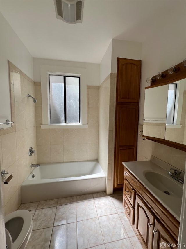 bathroom featuring vanity, tile walls, tiled shower / bath combo, and tile patterned flooring