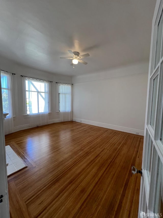 empty room with hardwood / wood-style floors and ceiling fan