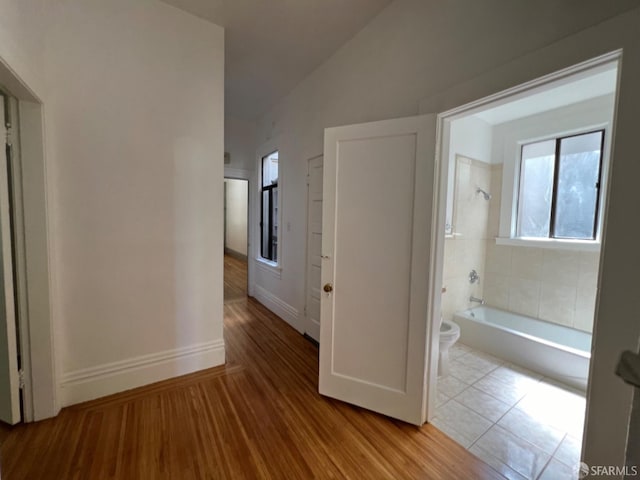 hallway featuring light wood-type flooring and lofted ceiling