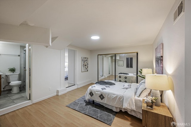 bedroom featuring ensuite bathroom and light hardwood / wood-style flooring