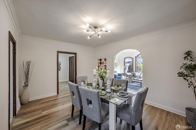 dining room with wood-type flooring, crown molding, and a notable chandelier