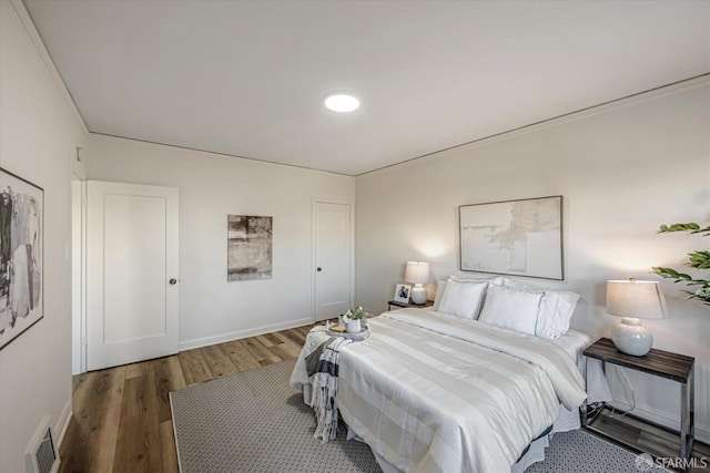 bedroom featuring crown molding and dark wood-type flooring