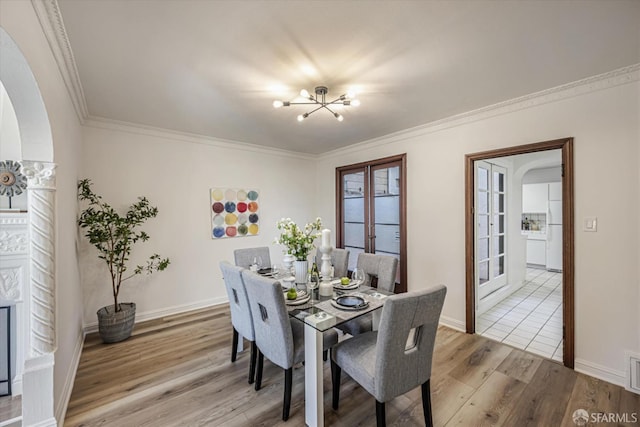 dining space with light hardwood / wood-style flooring, ornamental molding, french doors, and a notable chandelier