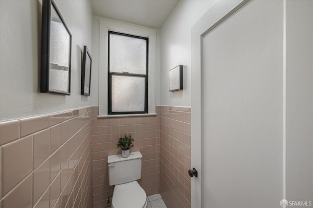 bathroom with toilet and tile walls