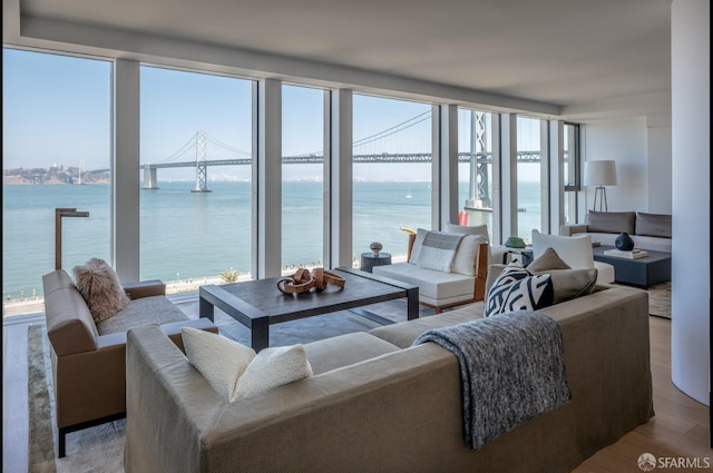 living area with a water view, expansive windows, and wood finished floors