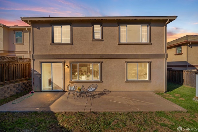 back house at dusk featuring a patio