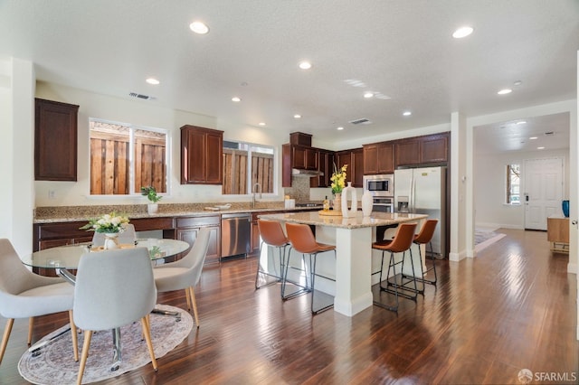 kitchen featuring dark hardwood / wood-style floors, a breakfast bar area, appliances with stainless steel finishes, and a kitchen island