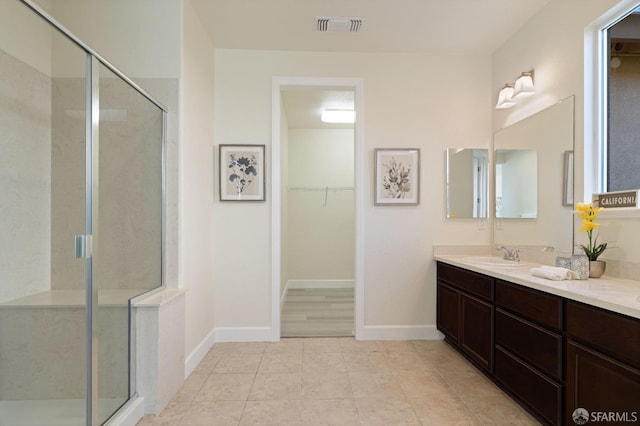 bathroom featuring tile patterned flooring, vanity, and a shower with shower door