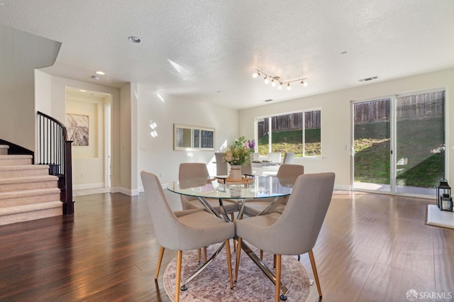 dining space featuring dark wood-type flooring and a textured ceiling