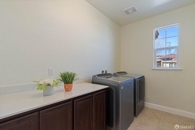 laundry area featuring cabinets, light tile patterned flooring, and washer and dryer