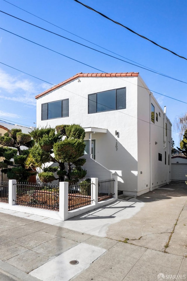 view of front of home featuring a garage, a fenced front yard, and stucco siding