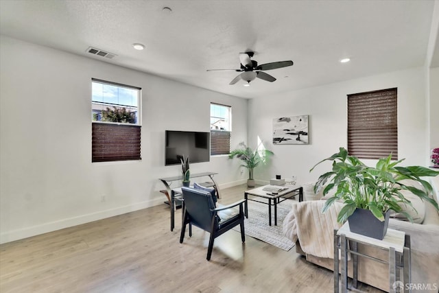 living room featuring ceiling fan, light wood-type flooring, and a wealth of natural light