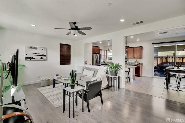 living room featuring ceiling fan, a healthy amount of sunlight, and light wood-type flooring