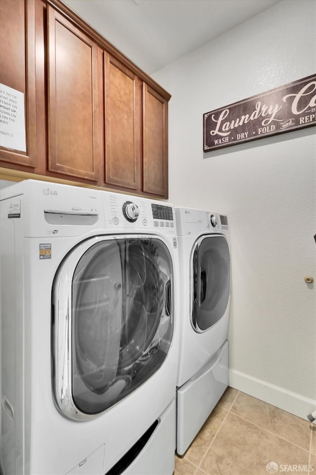 clothes washing area featuring cabinets, separate washer and dryer, and light tile patterned floors