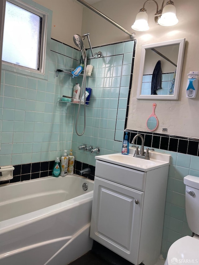 full bathroom with tiled shower / bath, vanity, toilet, and tile walls