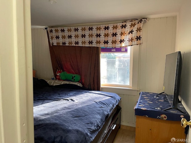 bedroom with hardwood / wood-style flooring and wood walls