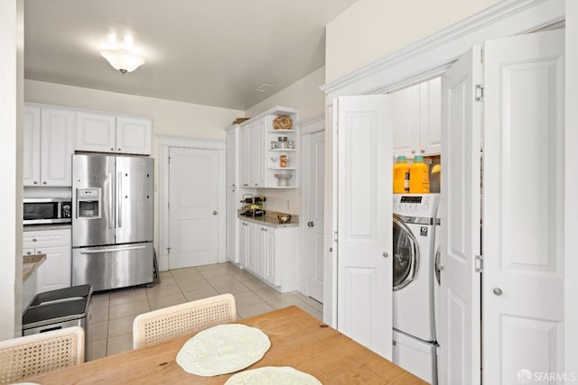 kitchen with washer / dryer, light tile patterned floors, stainless steel appliances, and white cabinetry