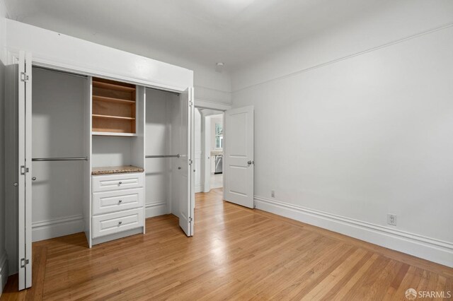 unfurnished bedroom with light wood-type flooring and a closet