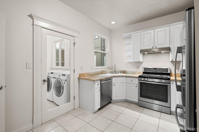 kitchen with stainless steel appliances, sink, washing machine and clothes dryer, white cabinets, and light tile patterned flooring