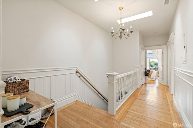 hall with wood-type flooring and an inviting chandelier