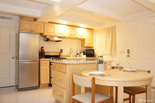 kitchen featuring light brown cabinets, light tile patterned floors, fridge, kitchen peninsula, and range with gas cooktop