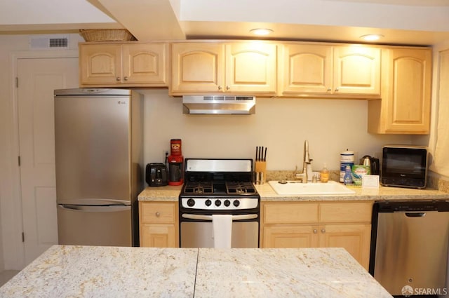 kitchen with light stone countertops, appliances with stainless steel finishes, sink, exhaust hood, and light brown cabinets