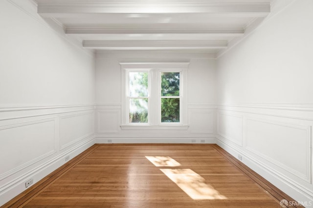 empty room featuring hardwood / wood-style floors and beamed ceiling