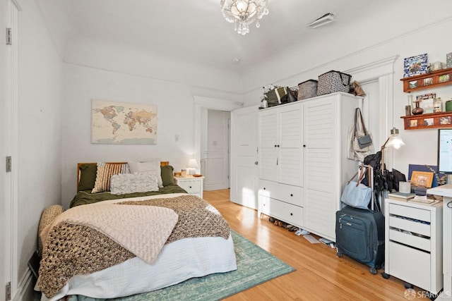 bedroom with hardwood / wood-style floors and a notable chandelier