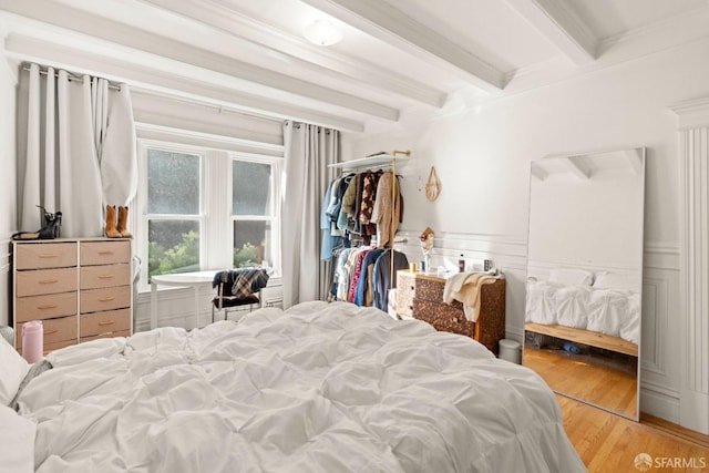 bedroom with hardwood / wood-style flooring, beam ceiling, and a closet